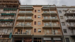 Un immeuble résidentiel à plusieurs étages, doté de balcons, d’une entrée sécurisée et d’un panneau indiquant une zone où le stationnement est interdit.