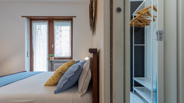 Une chambre à coucher avec un lit, des oreillers, une fenêtre et une vue sur l’extérieur.
