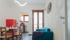 Un espace de vie compact comprenant un coin repas, un canapé de couleur turquoise et un appareil électroménager rouge.