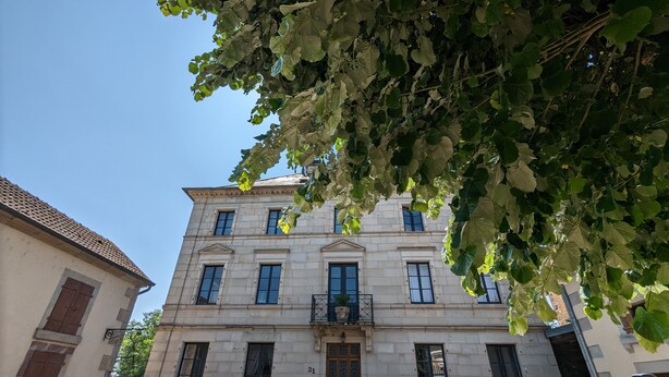 Un edificio histórico con fachada simétrica, múltiples ventanas y una entrada central con un balcón decorativo.
