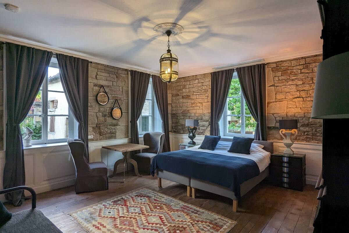 Ein Schlafzimmer mit Steinwand, einem Bett, einem Schreibtisch und einem Stuhl.