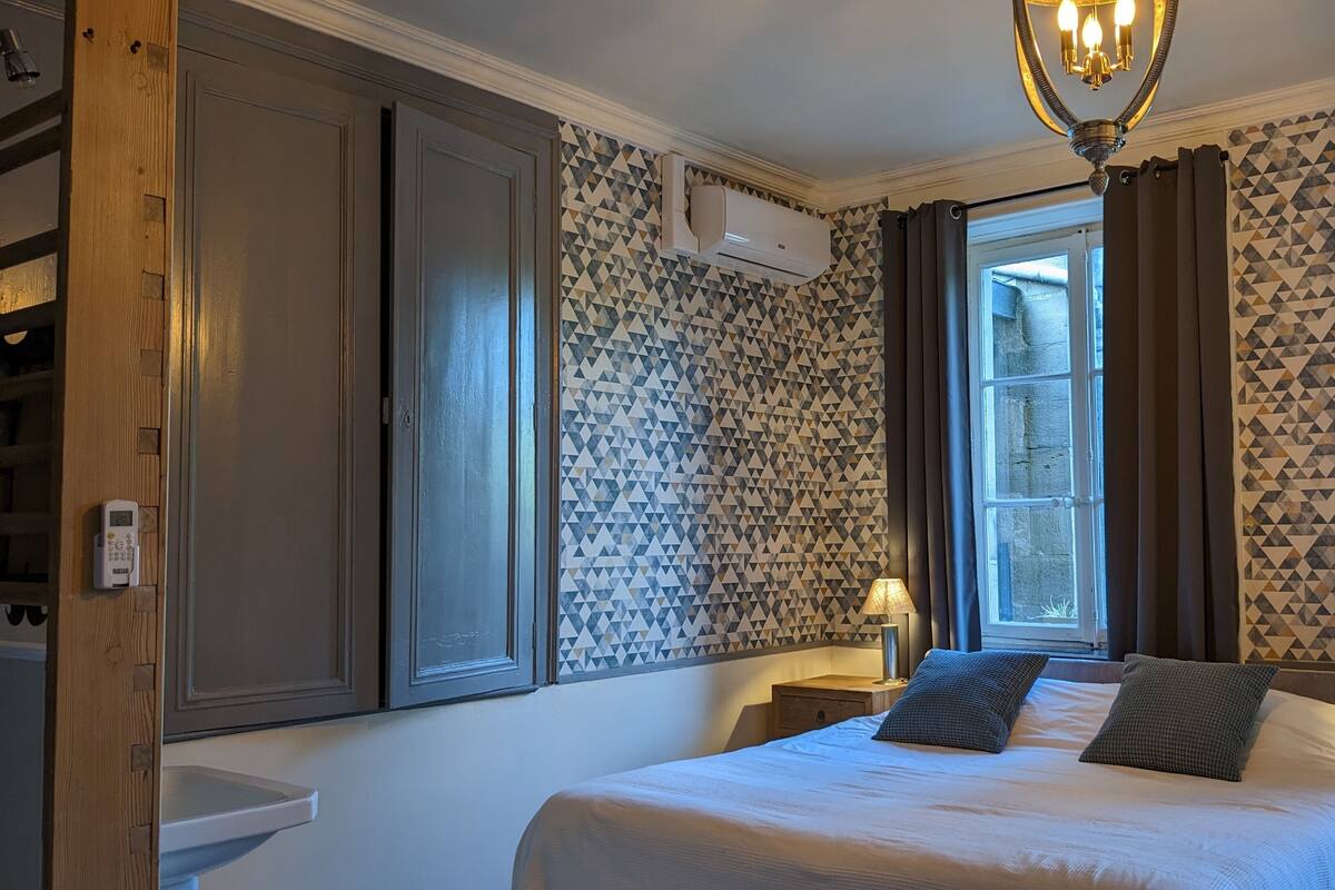 Ein Schlafzimmer mit Bett, Nachttischen, einem Fenster und strukturierter Wandgestaltung.