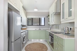 A compact kitchen with a stainless steel refrigerator, a washing machine, and a microwave. - Witsand 804 (Cape Town)