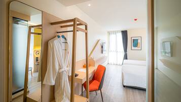 Una habitación de hotel con un escritorio de madera, una silla, una cama y un espejo grande.