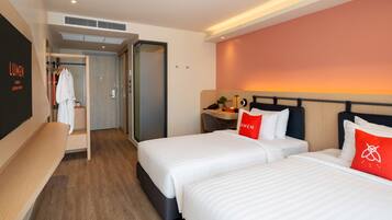 A hotel room with two beds, a desk, a chair, a wardrobe, and a bathroom.