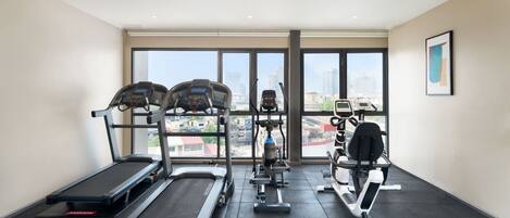 Un gimnasio con cintas de correr, elípticas y equipos de pesas.