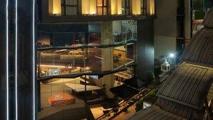 Un hôtel moderne à plusieurs étages, doté de grandes fenêtres et d’une terrasse sur le toit.