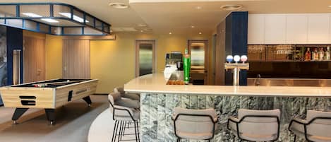 A modern kitchen with a bar area, a pool table, and a seating arrangement.