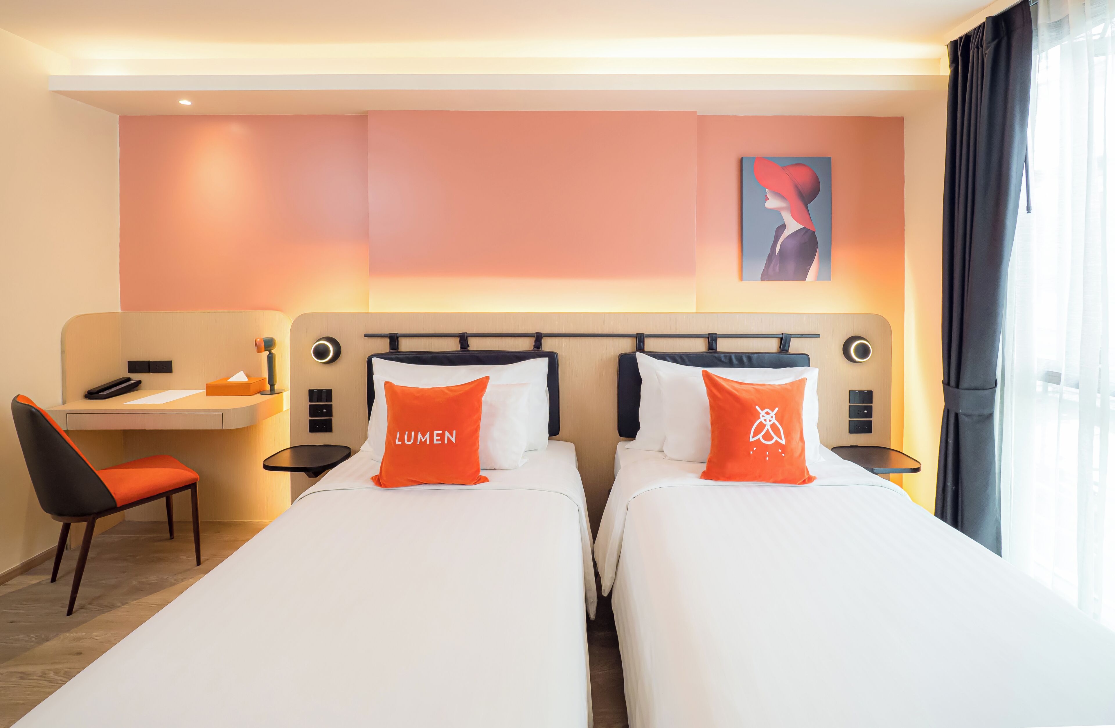 A hotel room with two beds, a desk, a chair, and a painting on the wall.
