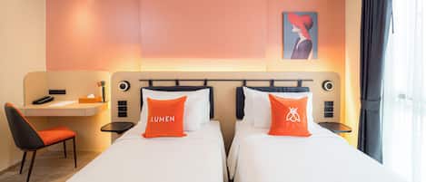 Una habitación de hotel con dos camas, un escritorio, una silla y un cuadro en la pared.
