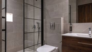A modern bathroom with a glass-enclosed shower, a white toilet, and a wooden vanity with a mirror.