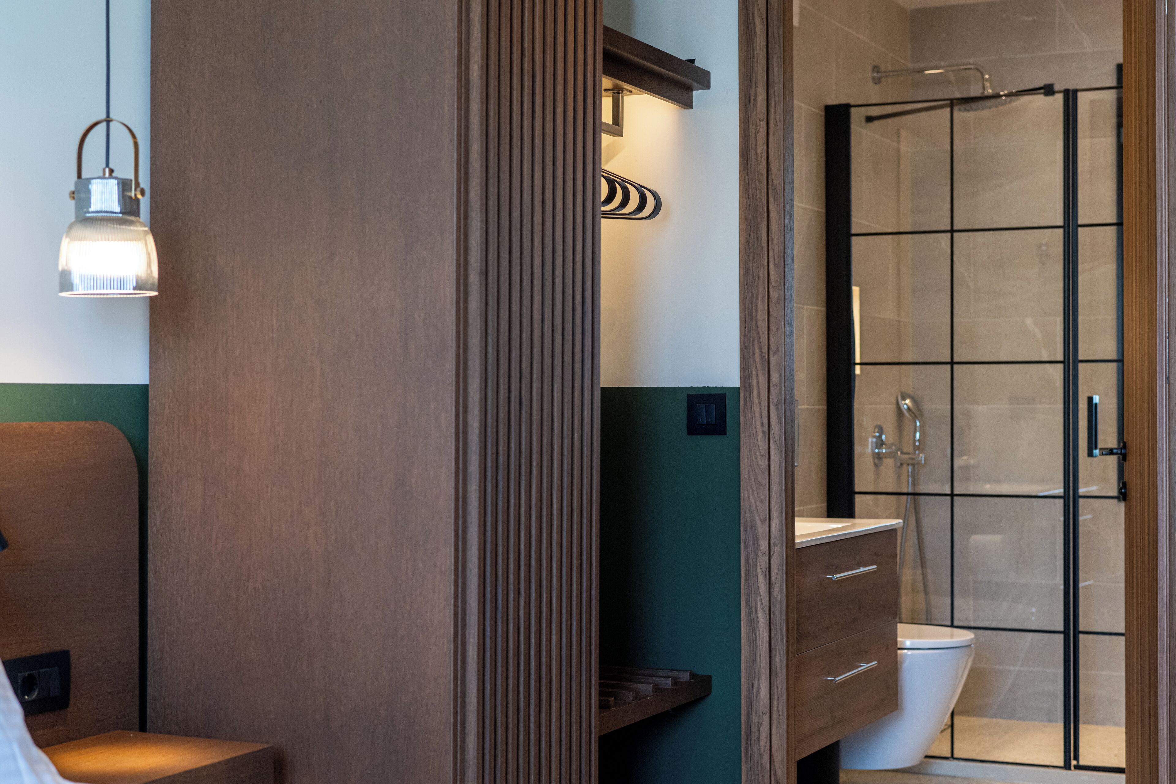 A modern bathroom with a wooden vanity, a toilet, and a glass shower enclosure.