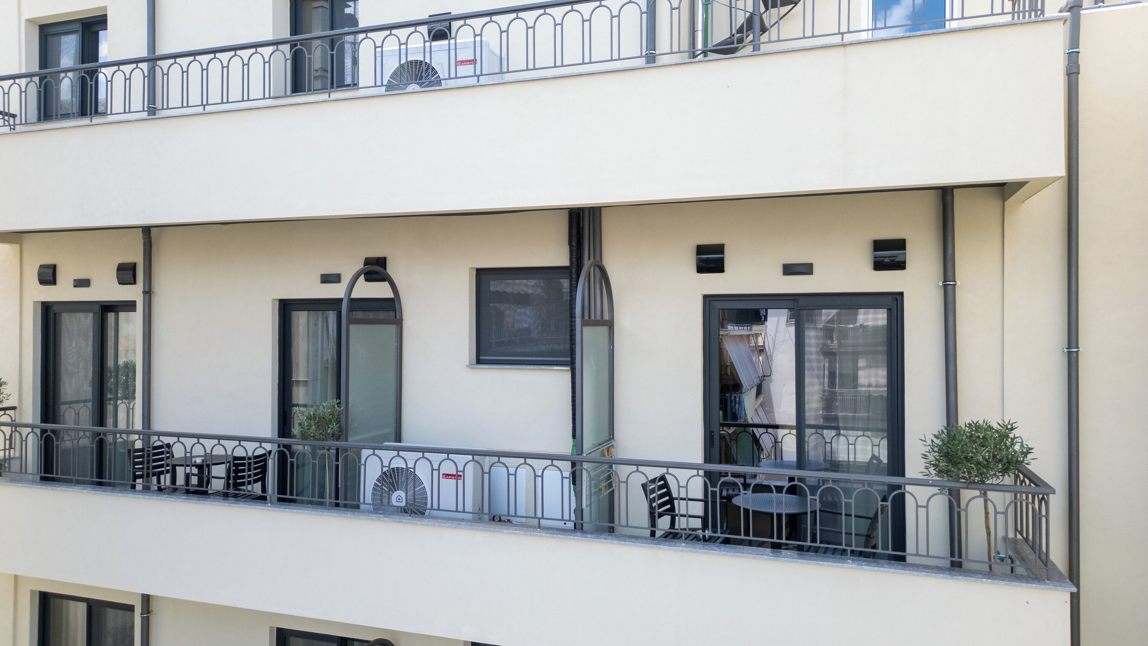 A multi-story building with balconies, outdoor seating, and a view of the street.