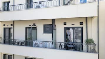 A multi-story building with balconies, outdoor seating, and a view of the street.