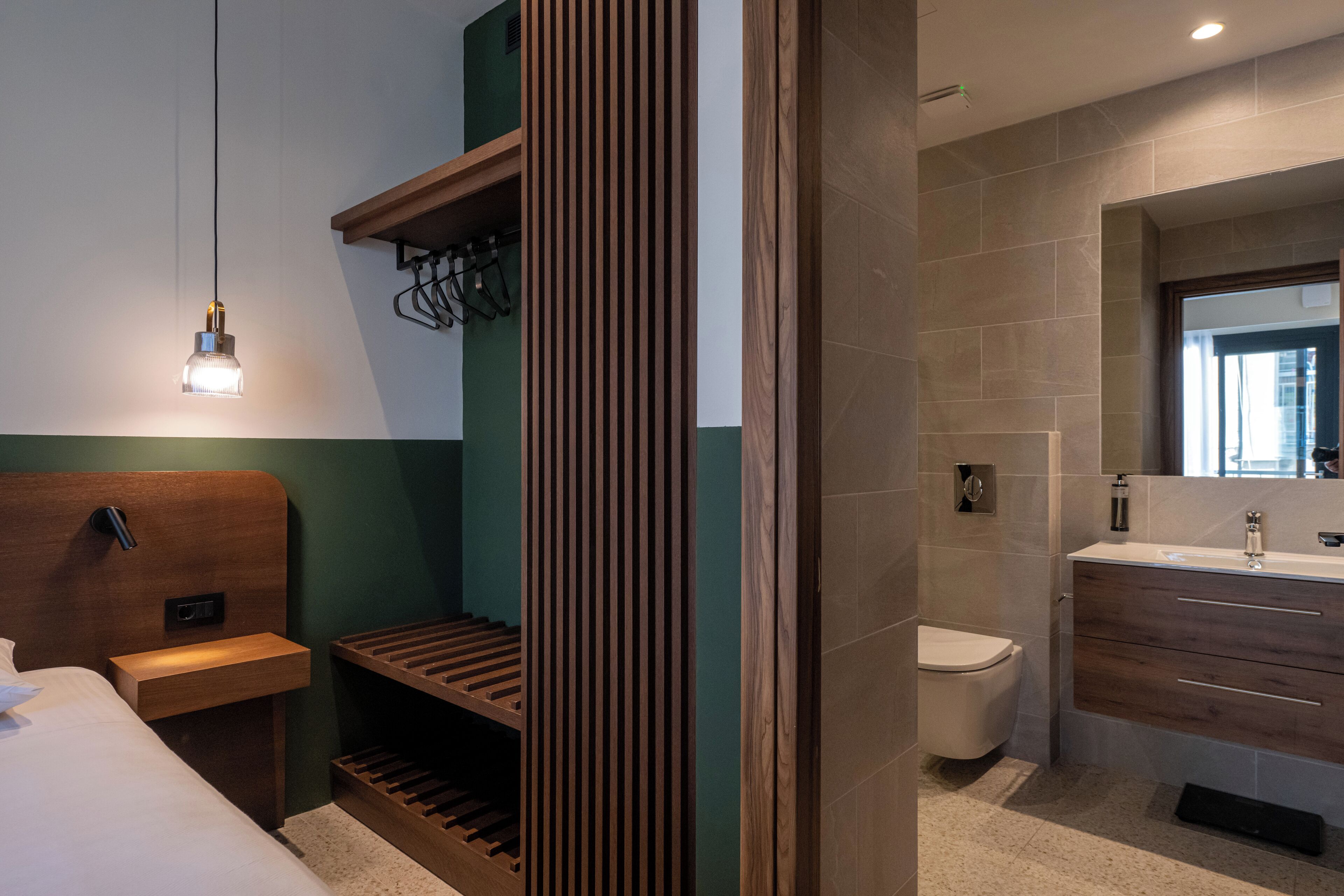 A modern bathroom with a wooden vanity, a toilet, and a built-in shelf.