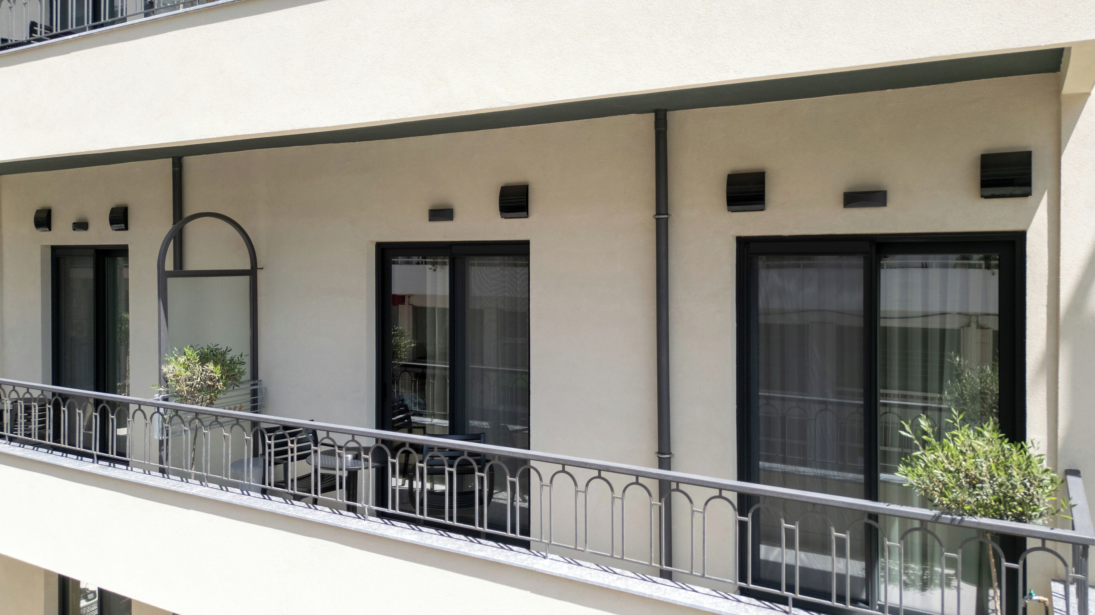 A building with a balcony, large windows, and a door.