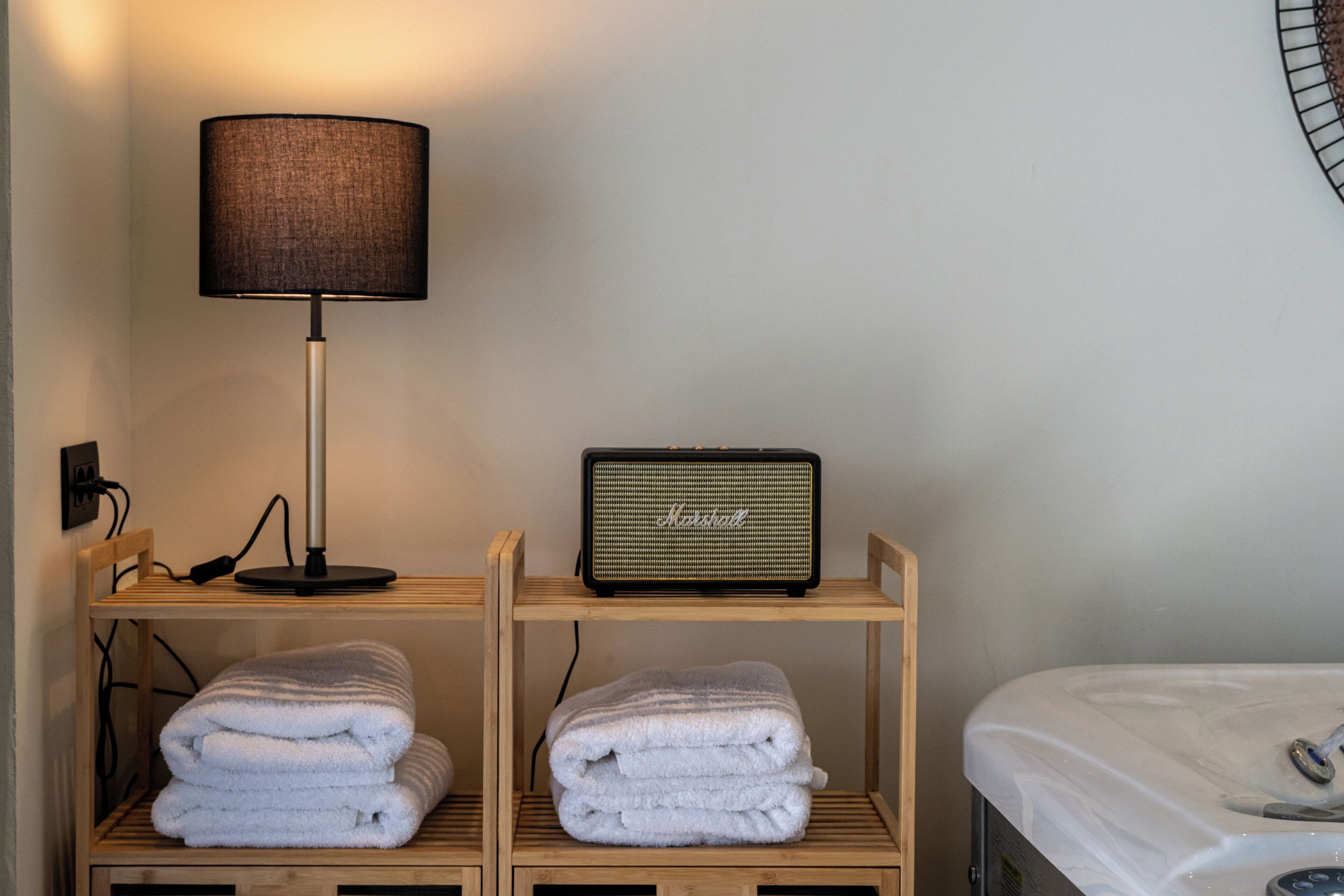 Et pænt hotelværelse med en lampe, en radio og håndklæder på træhylder.