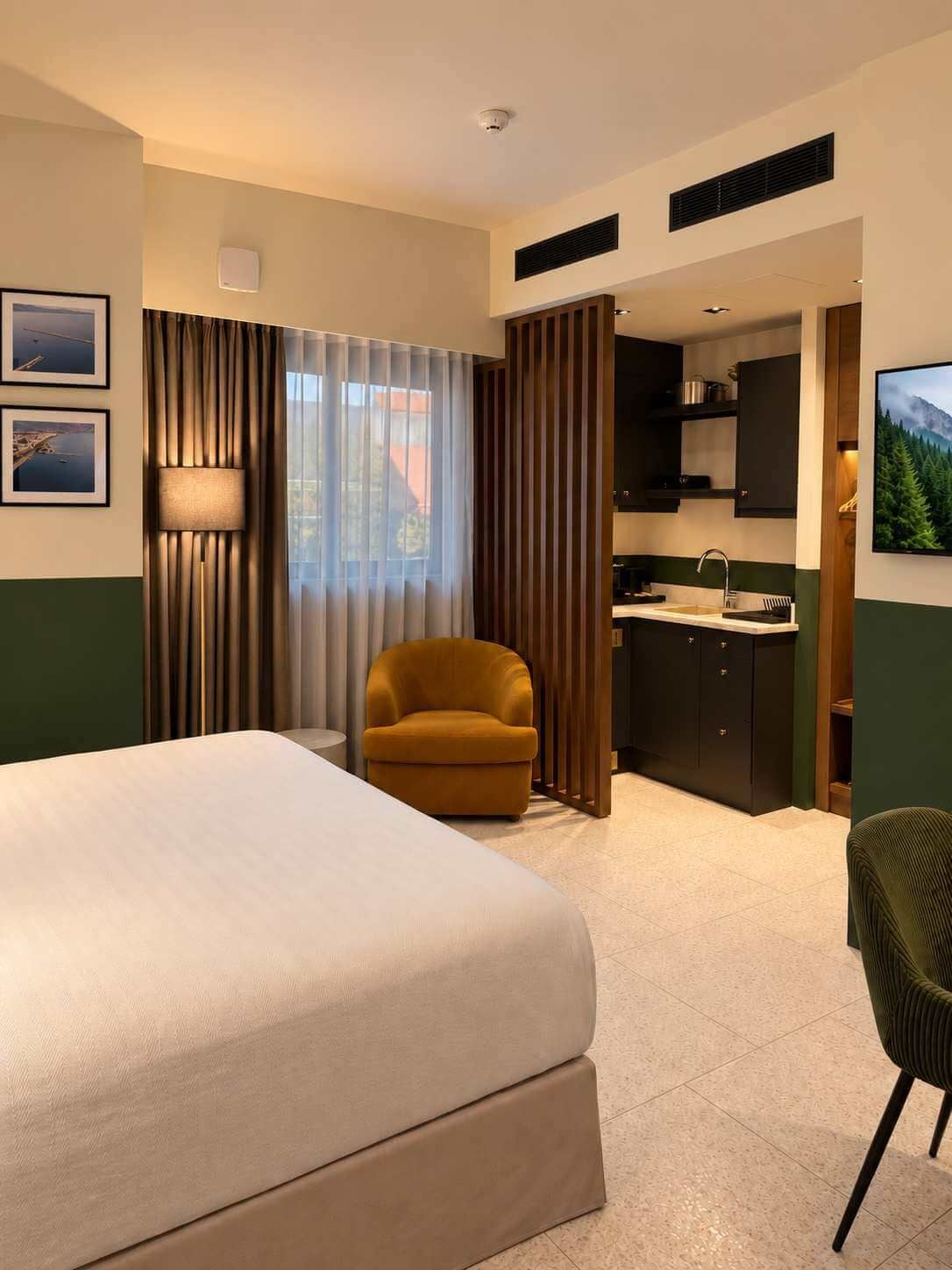 Une chambre d’hôtel comprenant un lit, une chaise, une kitchenette et un téléviseur.