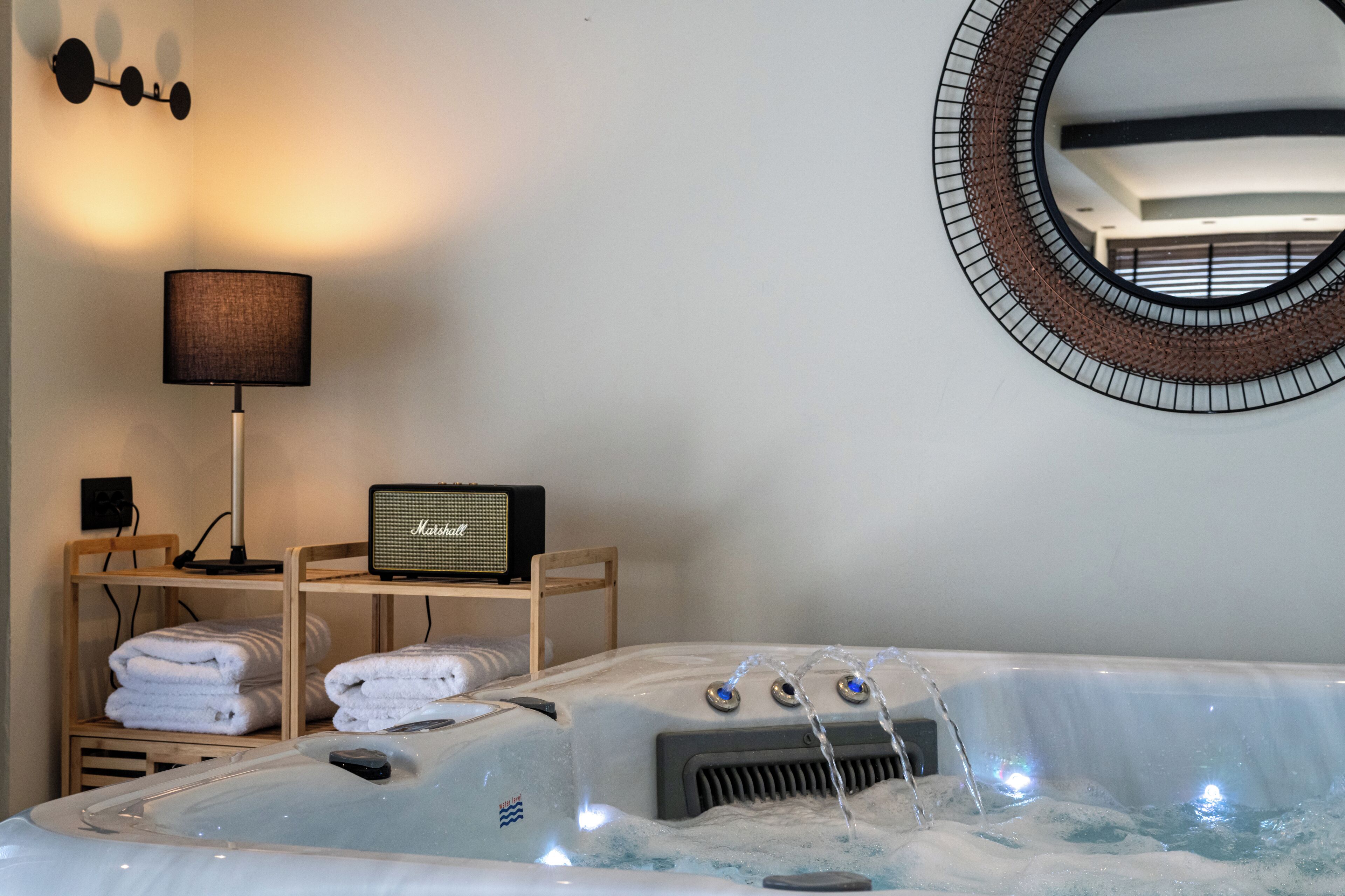 A modern bathroom with a hot tub, towels, a lamp, and a radio.