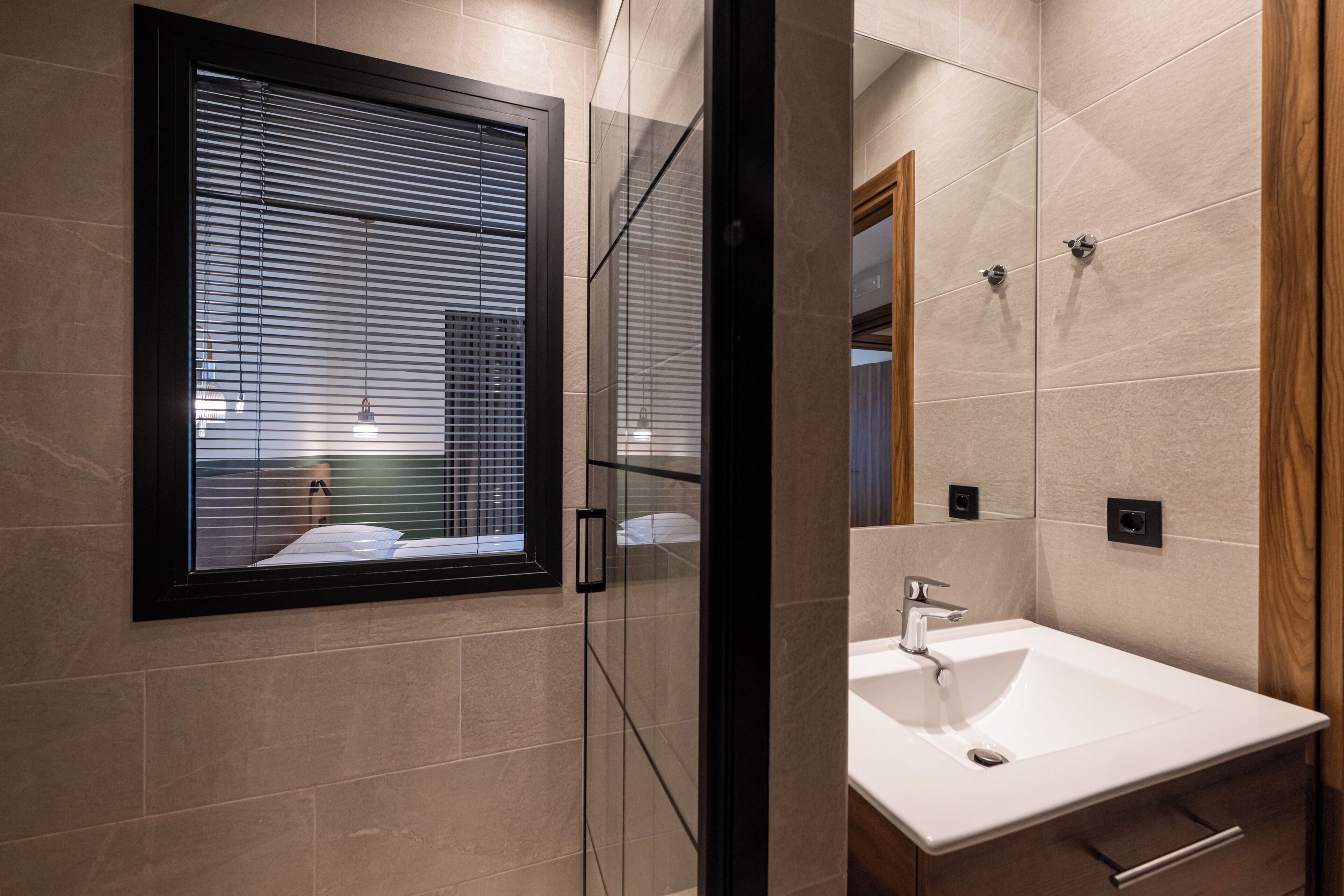 A modern bathroom with a large window, a sink, and a mirror.