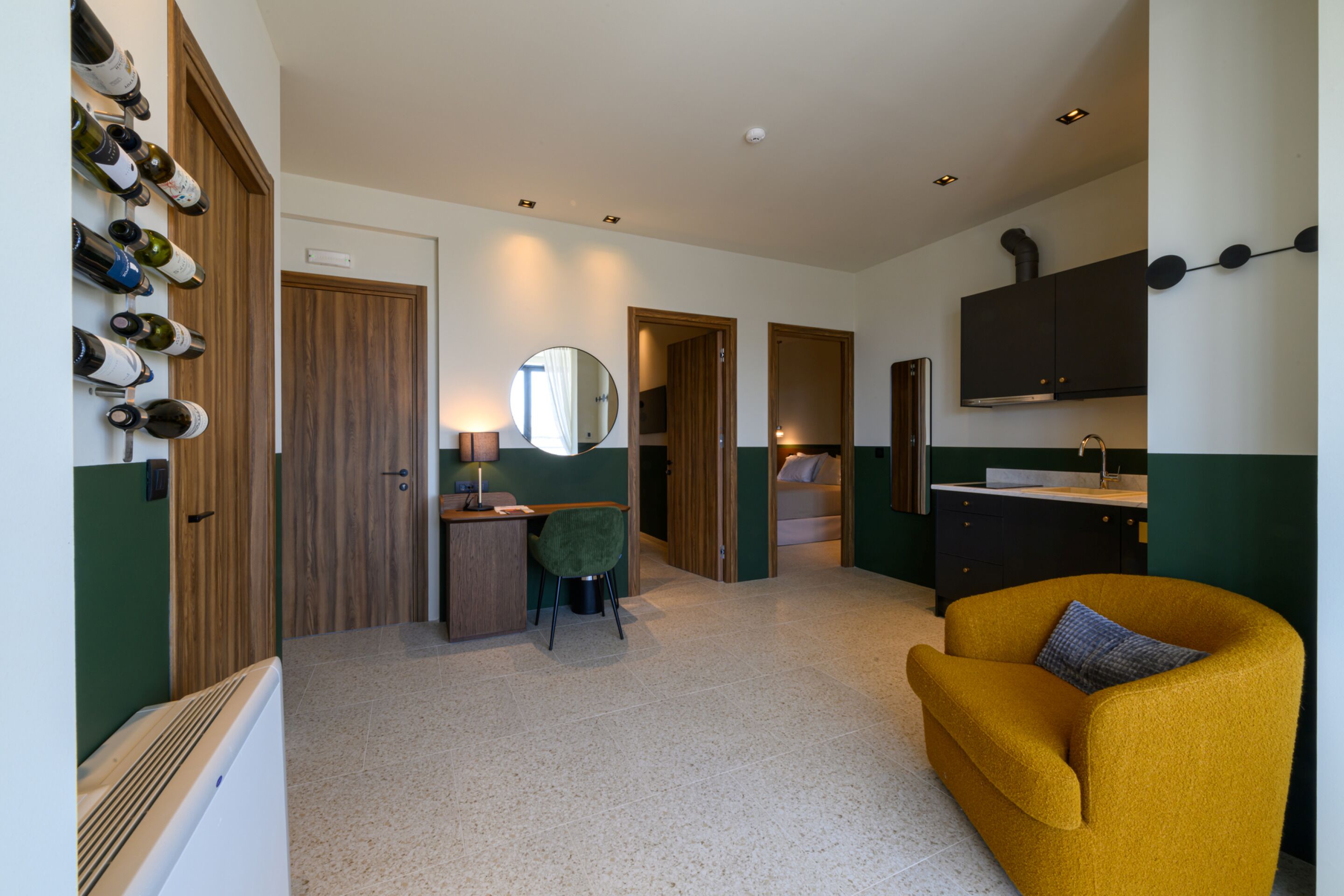 A hotel room with a bed, a desk with a chair, a mirror, a wardrobe, and a wall-mounted TV.