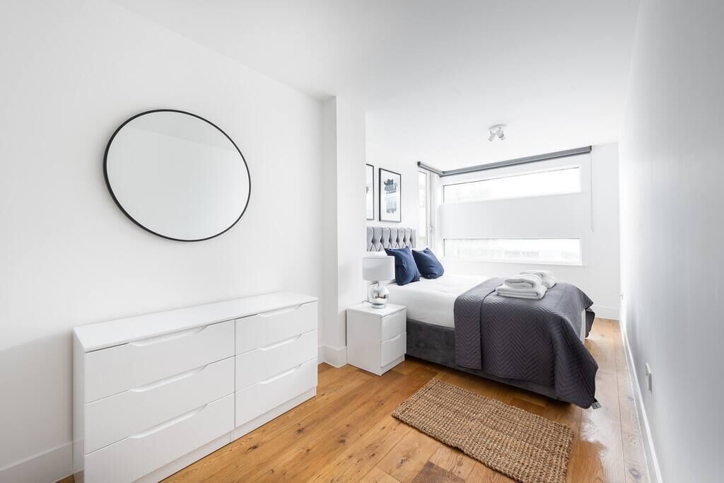 A modern bedroom with a bed, bedside table, and a large window.