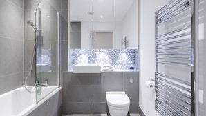 A modern bathroom with a glass-enclosed shower, a white toilet, and a chrome towel rack. - PBC | One Bedroom Apartment with Balcony JT4 (London)