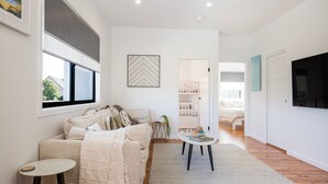A modern living room with a sofa, a coffee table, and a bookshelf. - Sandy Rays - 5 Mins Walk to Beach (Culburra Beach)