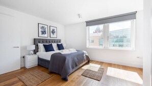 A modern bedroom with a bed, nightstands, and a large window. - PBC | One Bedroom Apartment with Balcony JT6 (London)