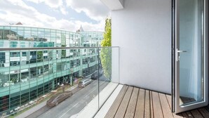A balcony with a view of a modern building with glass windows and a street below. - PBC | One Bedroom Apartment with Balcony JT6 (London)