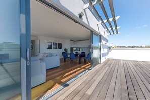 Un espace de vie moderne avec une porte vitrée donnant sur un balcon, un coin repas et une cuisine visible à travers la vitre.