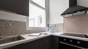 A modern kitchen with a stainless steel sink, a built-in oven, and a window providing natural light. - PBC | One Bed Apartment Earl's Court 121 EC2 (London)