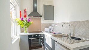 Ett kompakt kök med en inbyggd ugn, en diskho i rostfritt stål och en modern spis.