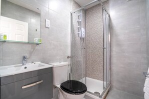 Enjoy a refreshing shower in this bathroom with a glass-enclosed shower area, white sink, and black toilet.