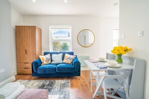 Relax in this stylish living space with a sofa, dining area, and large window offering a view of the surrounding greenery.