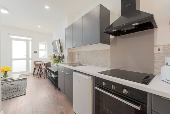 A modern kitchen with a built-in oven, a dishwasher, and a black range hood.