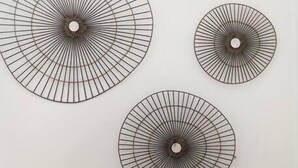 A wall with three circular wall art pieces and a lamp.