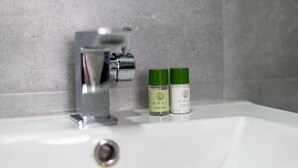 A bathroom sink with a chrome faucet and two bottles of Eden body wash.