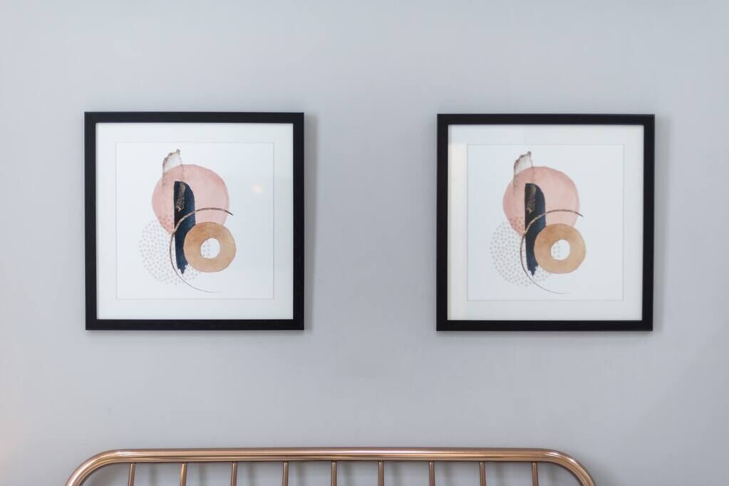 Two framed abstract artworks on a light gray wall.