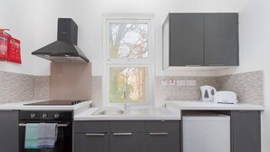 A modern kitchen with a stove, oven, sink, and cabinets. - PBC | Cosy 1-Bed Apt - Earl's Court 119 - EC3 (London)