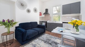 A modern kitchen with grey cabinets, a black range hood, and a window. - PBC | Cosy 1-Bed Apt - Earl's Court 119 - EC3 (London)
