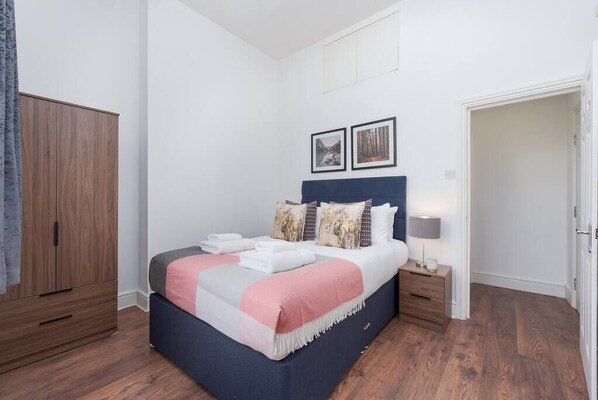 Cozy retreat with a large bed, bedside table, and wardrobe.