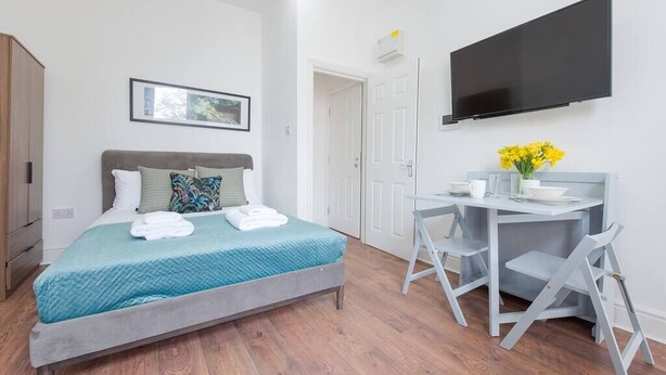 Een moderne slaapkamer met een bed, een bureau en een televisietoestel.