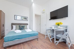 Un dormitorio moderno con una cama, un escritorio y un televisor.
