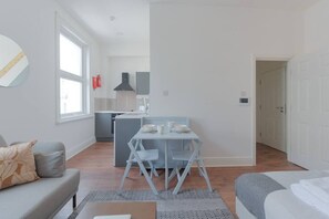 Un espace de vie moderne et compact comprenant un coin repas, une kitchenette et un coin salon confortable.
