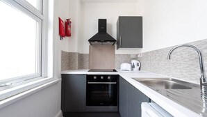 A compact kitchen with a stove, oven, and modern sink. - PBC | Large Studio - Earl's Court 119 - EC6 (London)