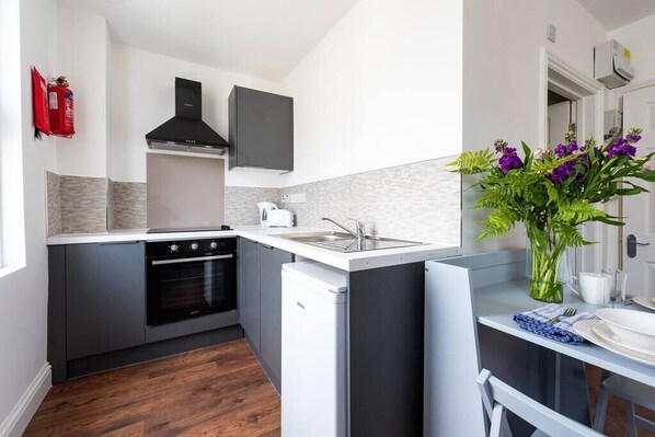 Enjoy cooking in this well-equipped kitchen with an oven, stainless steel range hood, and compact refrigerator.