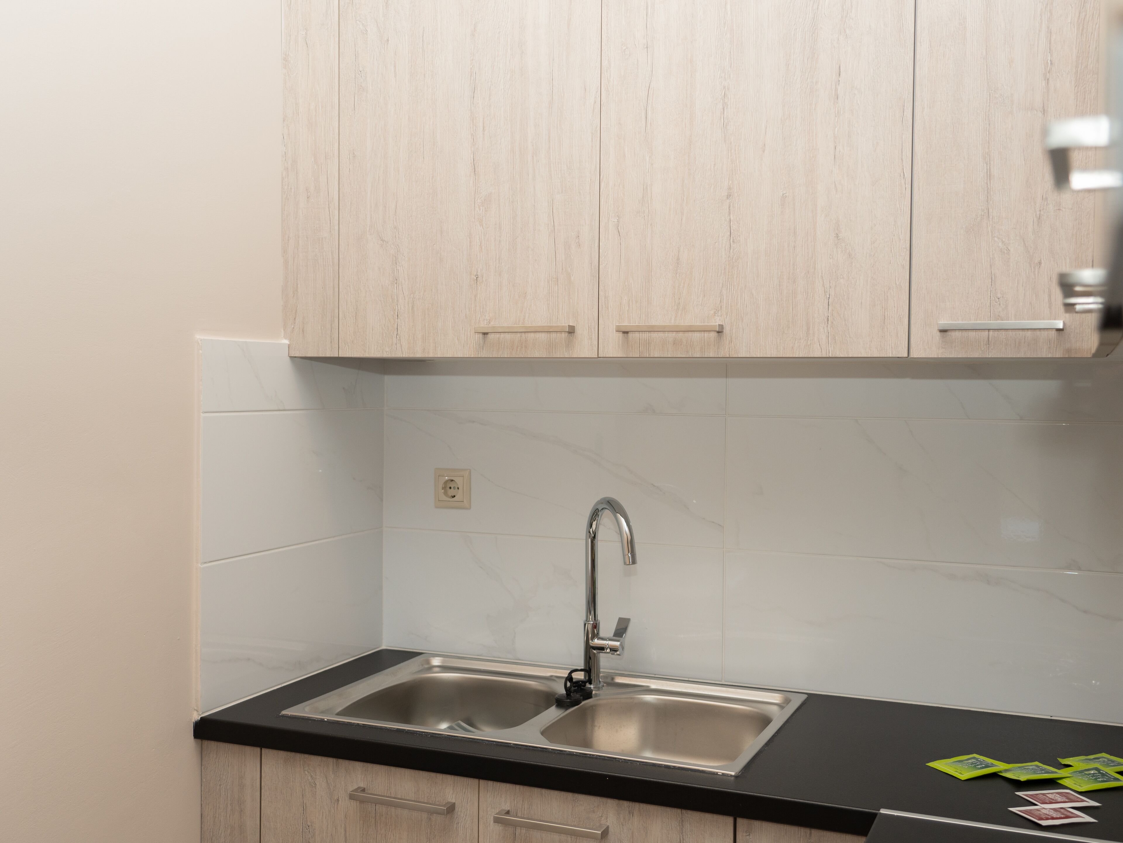 Eine Küche mit zwei Edelstahl-Spülen, Holzschränken und einer schwarzen Arbeitsplatte.