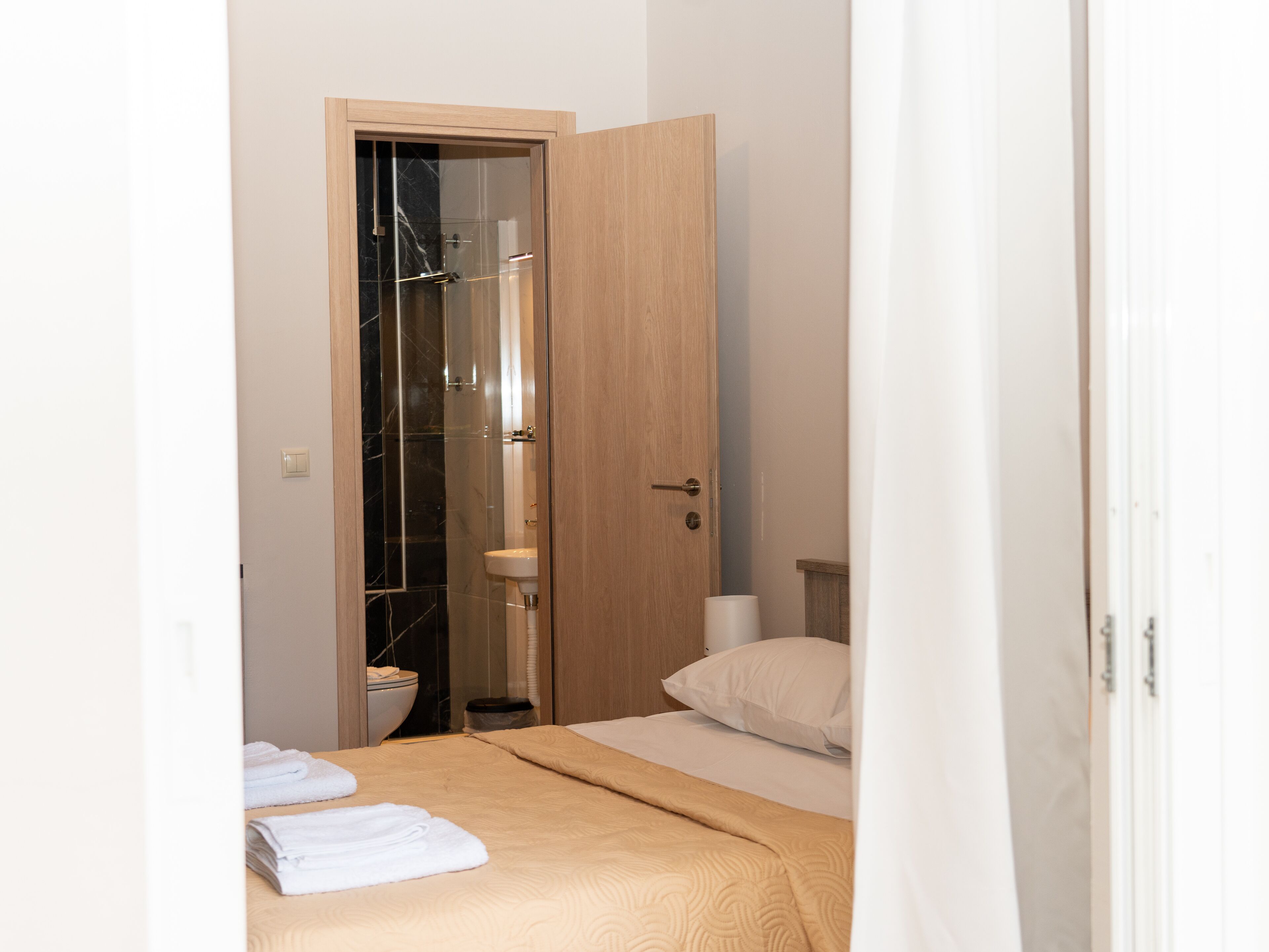 Une chambre d’hôtel avec un lit, une porte en bois, une salle de bain avec des toilettes et un lavabo.