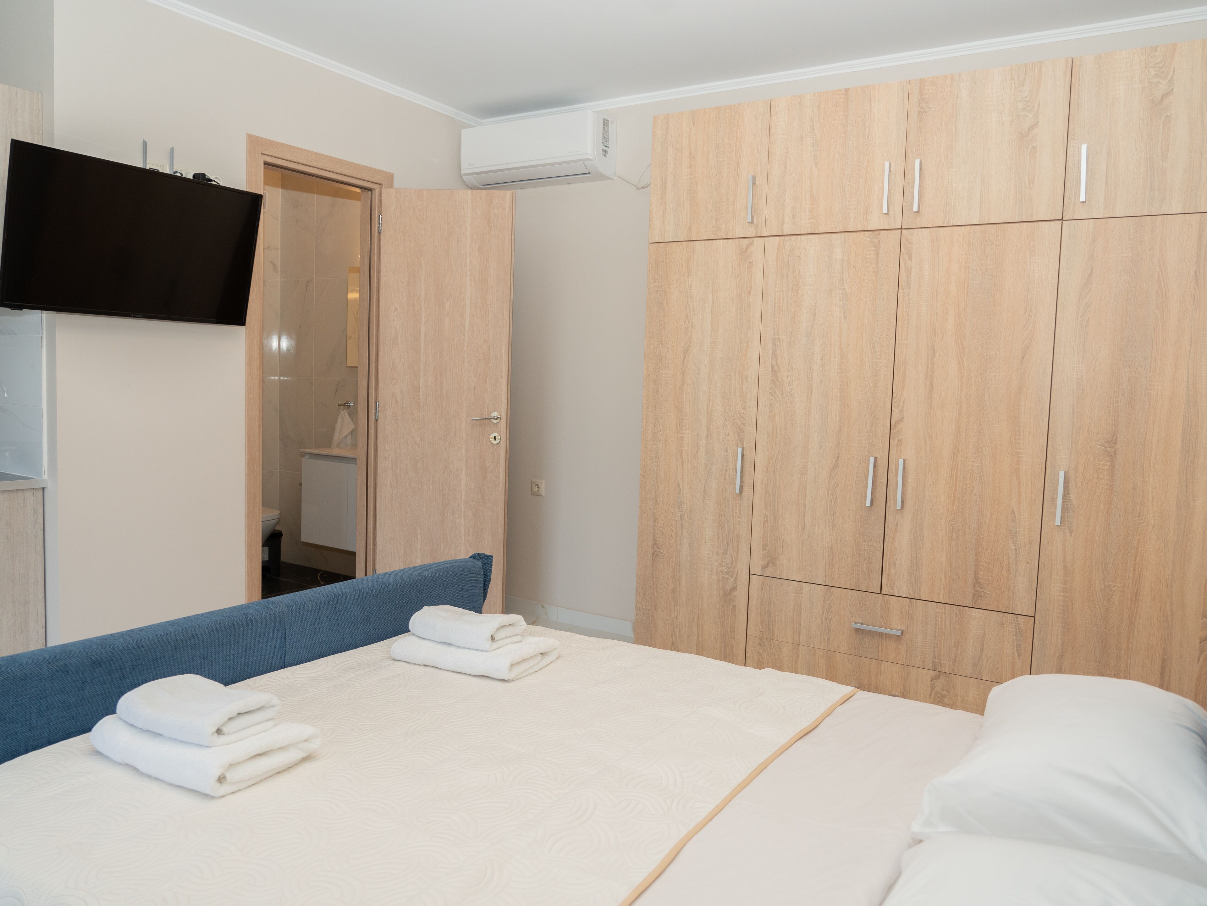 Un dormitorio con cama, armario y televisión en la pared.